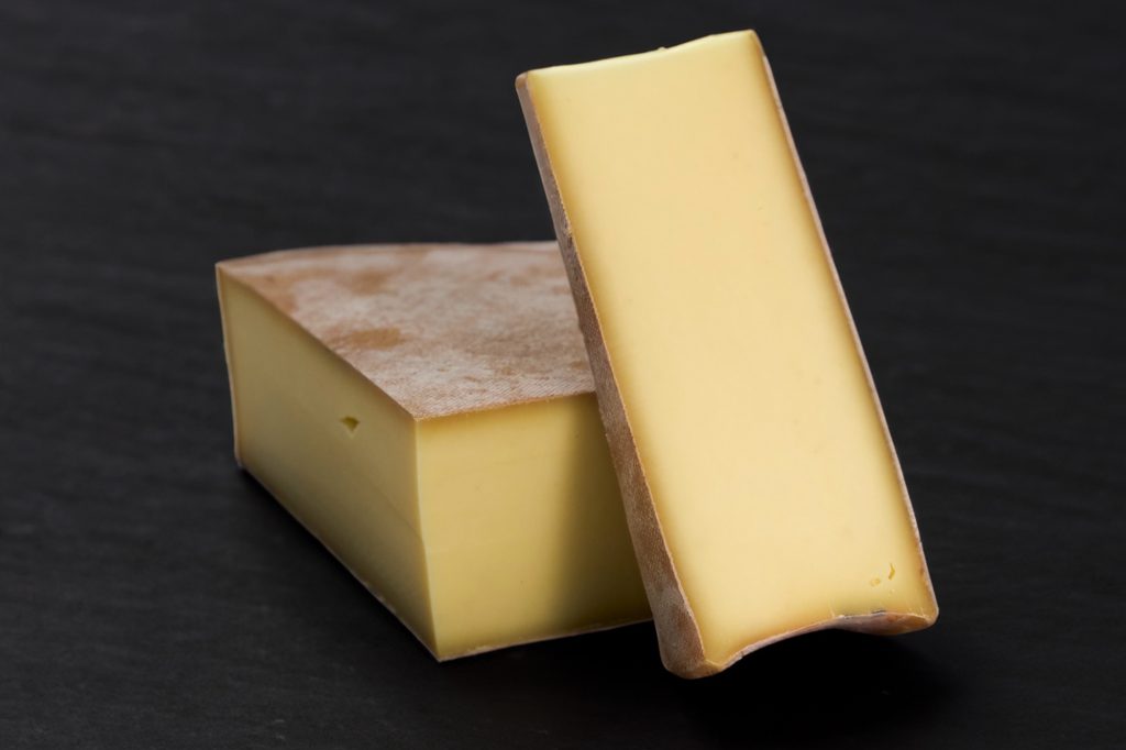 Portion d'Abondance et tranche de fromage à pâte ivoire sur une ardoise