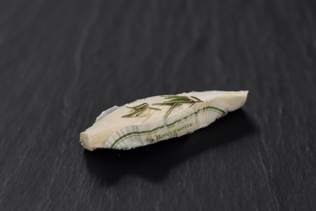 Bouyguette, petit chèvre frais emballé avec un brin de romarin, sur ardoise