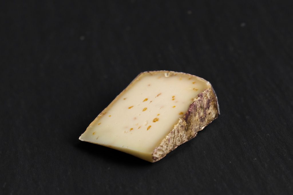 Portion de brebis au fenugrec, pâte pressée parsemée de graines, sur ardoise