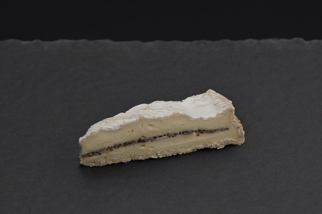 Pointe de Brie de Meaux à la truffe, couche de truffe noire visible, sur ardoise