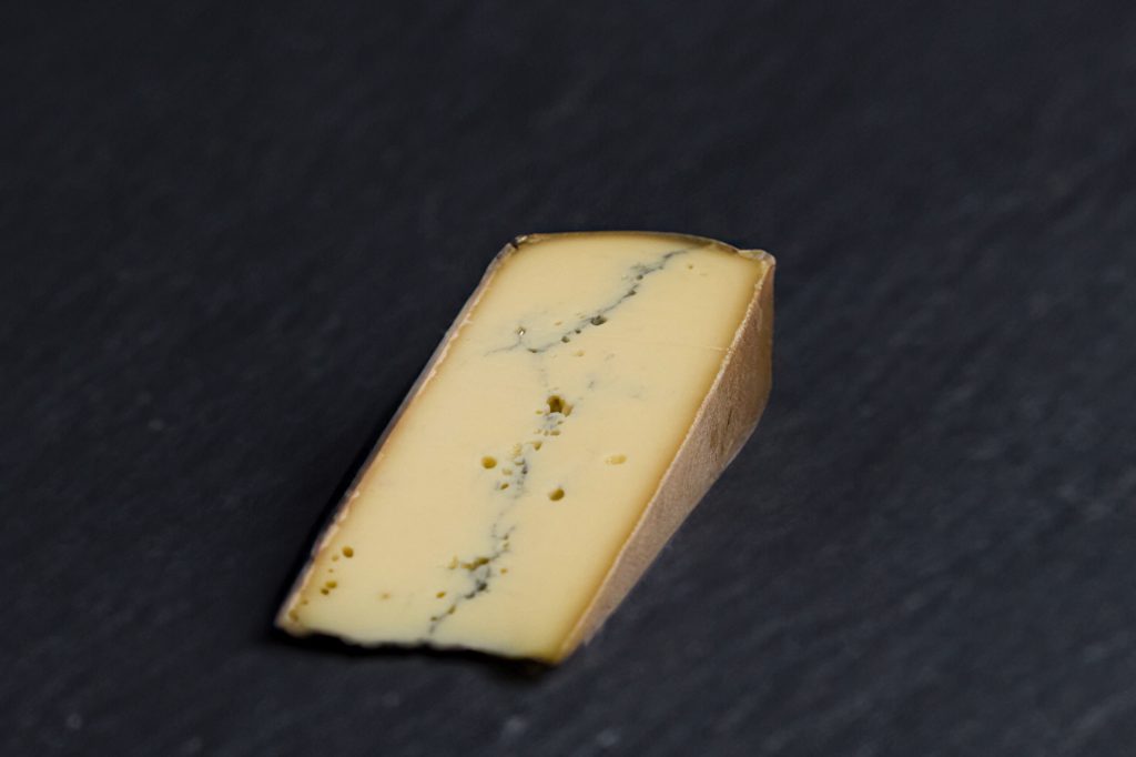 Portion de Morbier montrant sa raie de cendre au cœur, sur ardoise