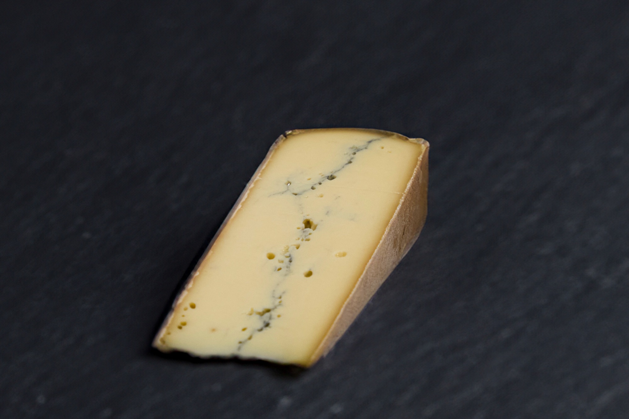 Portion de Morbier montrant sa raie de cendre au cœur, sur ardoise