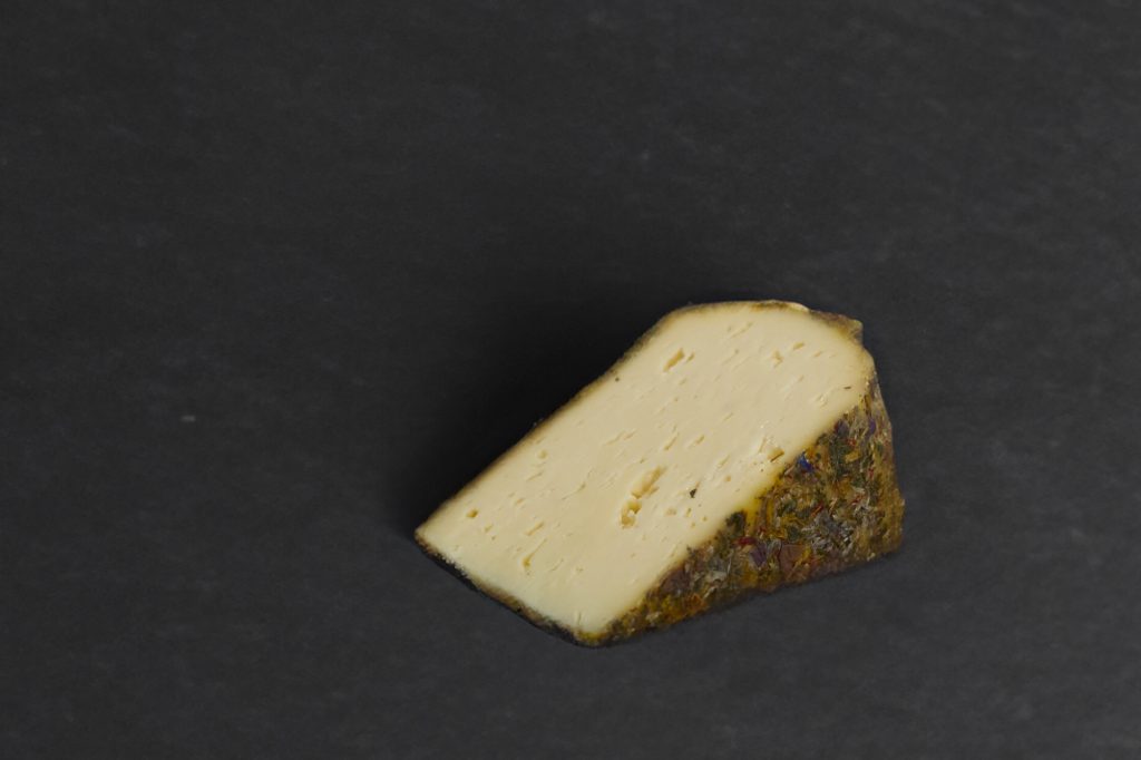 Portion de tomme aux fleurs, croûte de fleurs et d'herbes séchées, sur ardoise