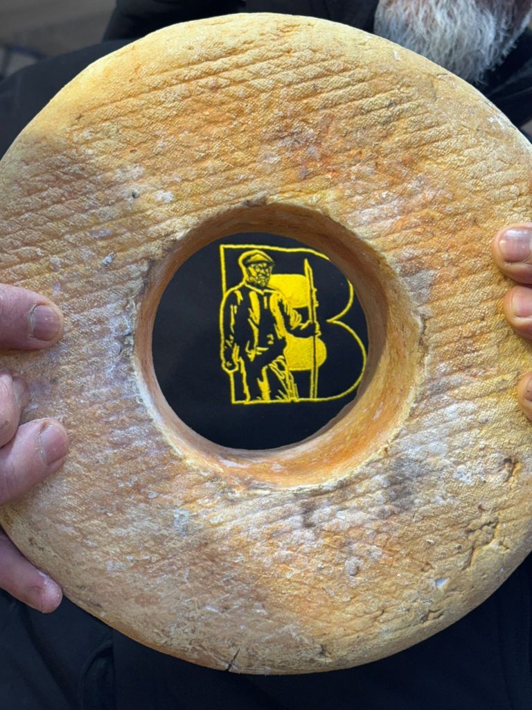 Meule marquée au logo du Berger, tenue à deux mains